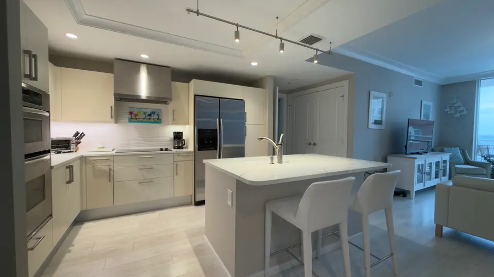 Modern kitchen with white quartz island, bar seating and stainless appliances