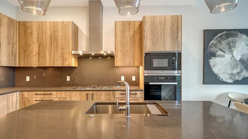 Contemporary kitchen with wood-grain cabinets, quartz island and pendant lights