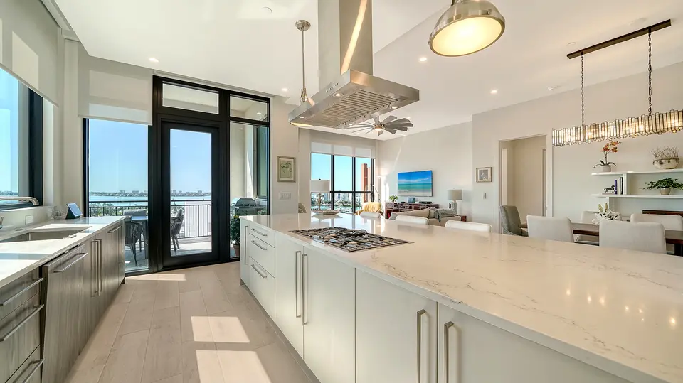 Open kitchen with long quartz island and bay views through glass doors