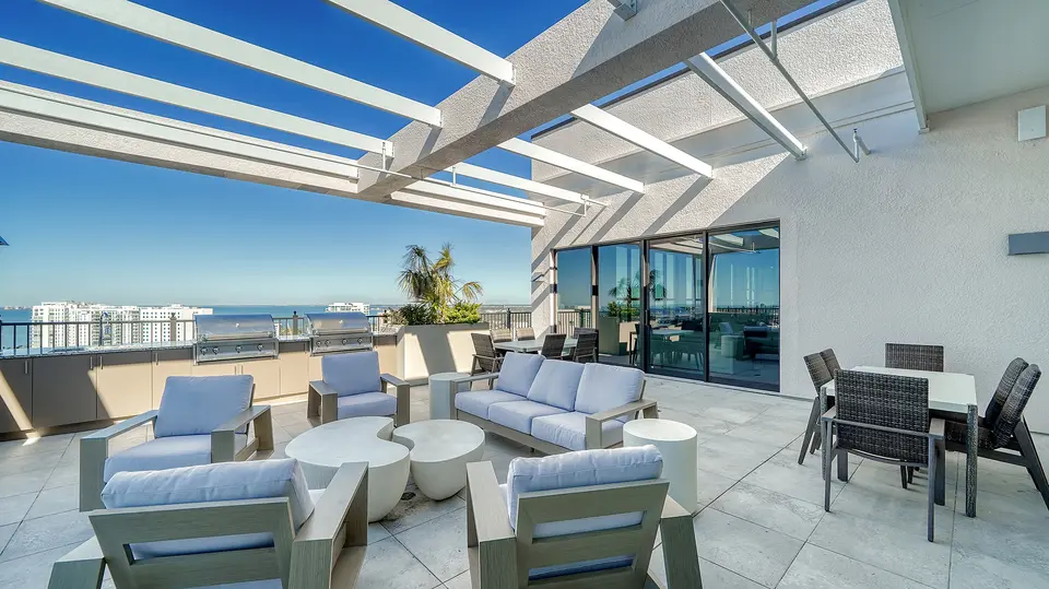 Rooftop terrace with lounge seating under a pergola and bay views