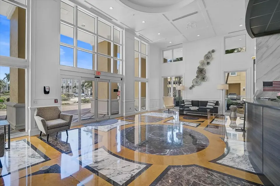 Bright two-story condo lobby with inlaid marble floor and lounge seating