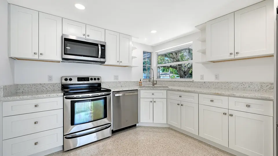 Bright white kitchen with stainless appliances and granite counters