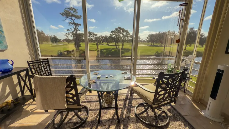 Screened lanai with a dining set overlooking a golf course