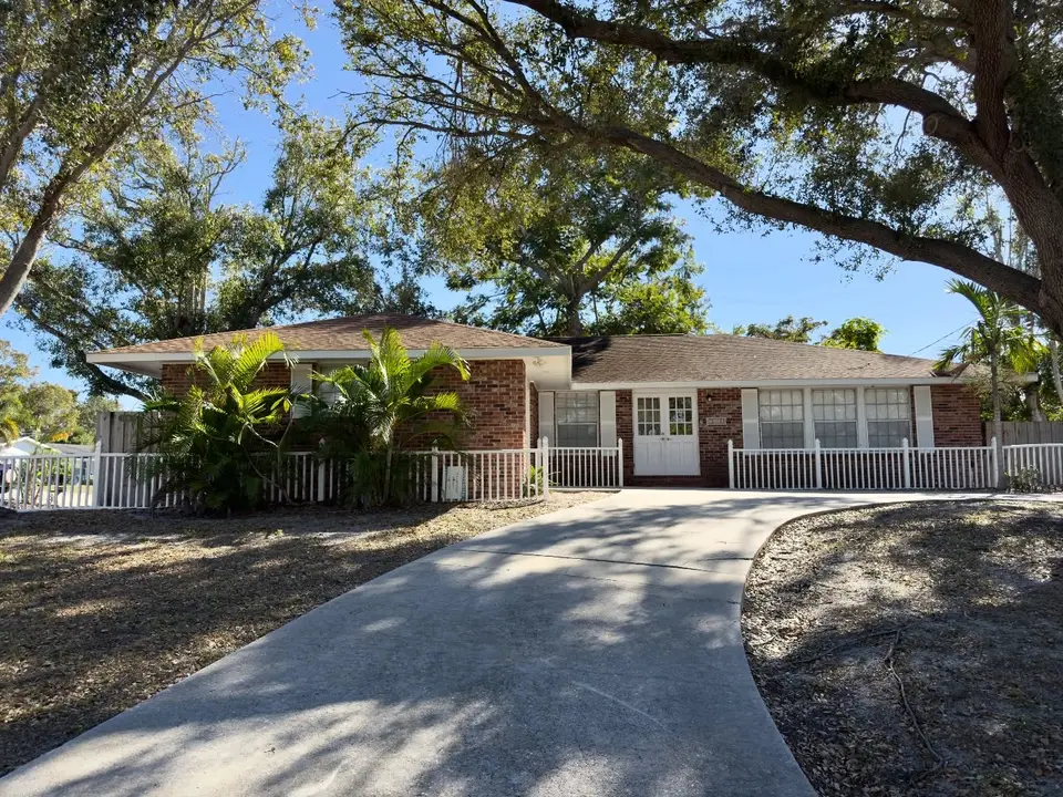 Single-story home with a long driveway under a large oak