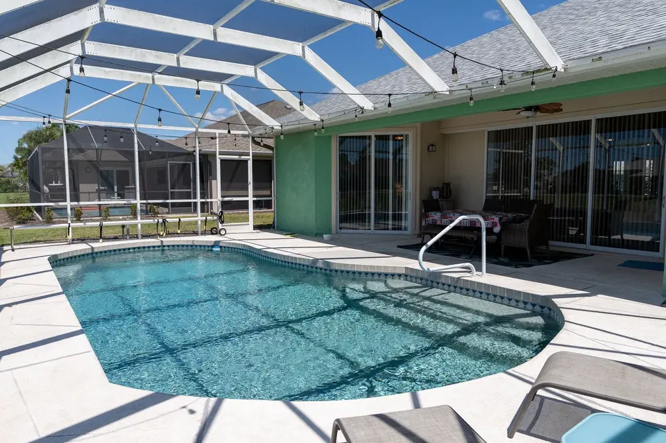 Screened pool and lanai behind a green canal-front home