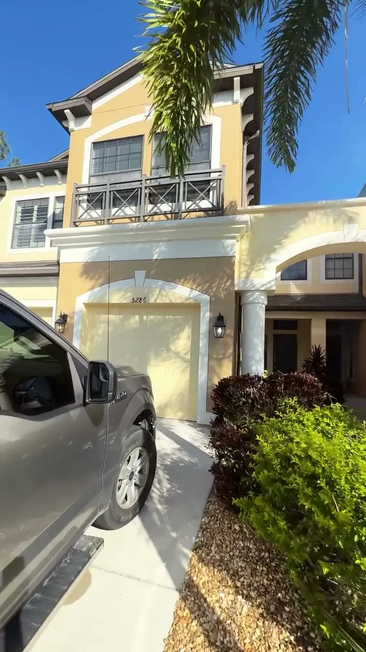 Two-story townhome entry with a garage and palms