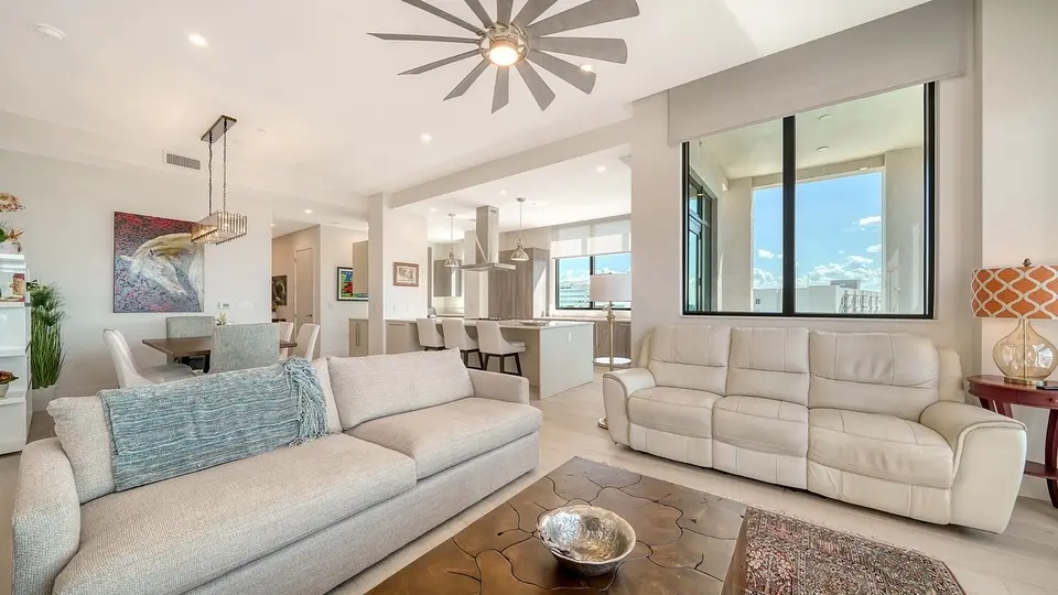Bright condo living room with white sofas and a view