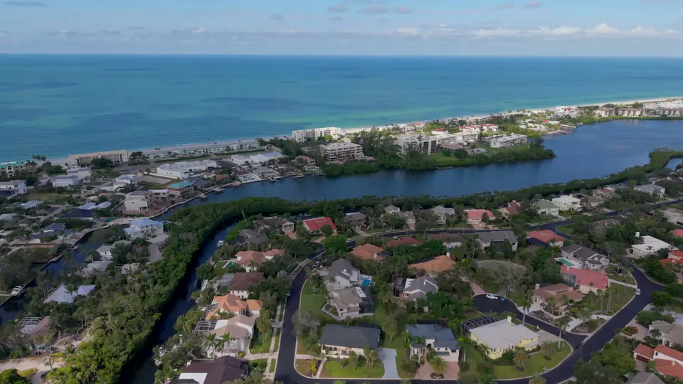 Aerial over Bay Isles homes and waterway with the Gulf of Mexico on the horizon