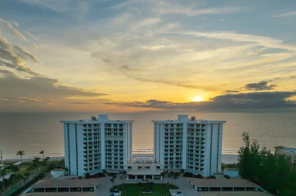 Twin beachfront condominium towers on the Gulf at sunset, seen from above