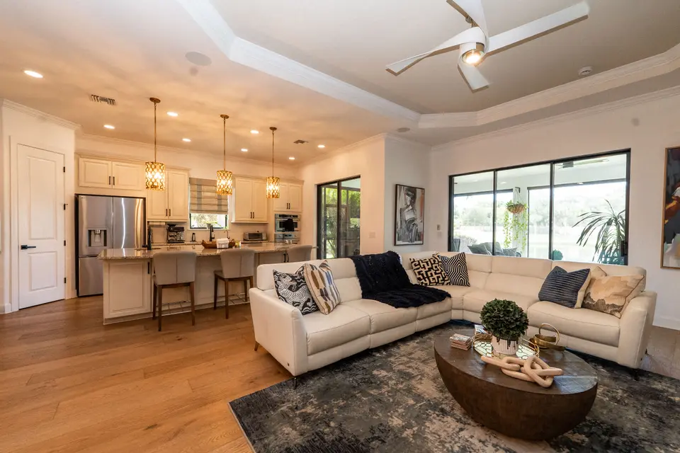 Open great room with sectional seating, wood floors and kitchen beyond