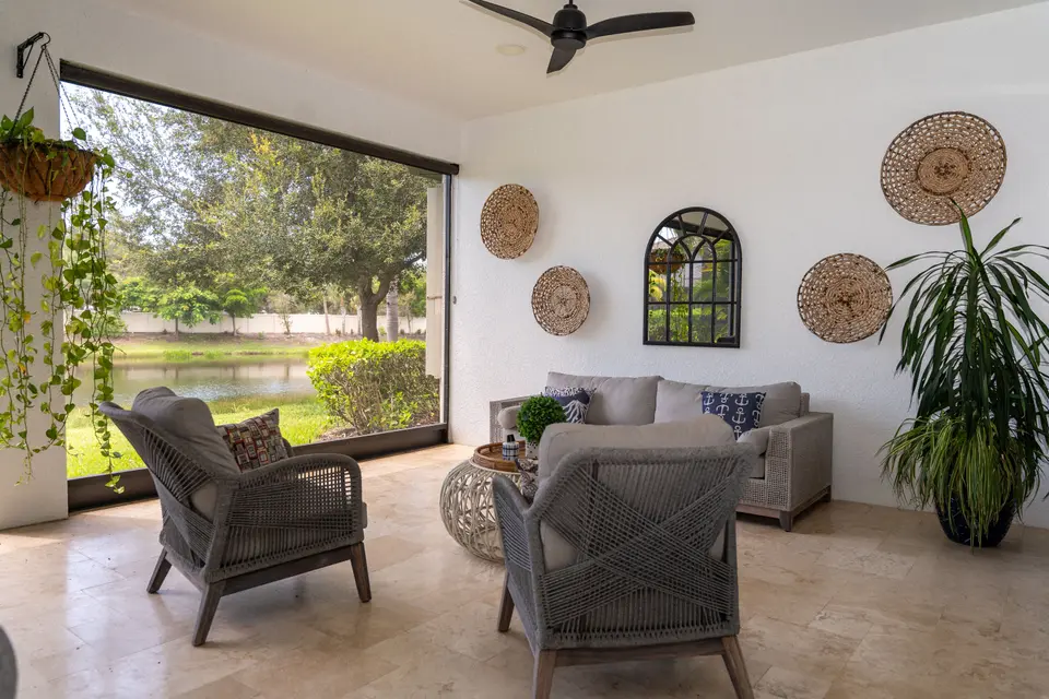 Covered lanai with wicker seating that opens to a lawn and lake view