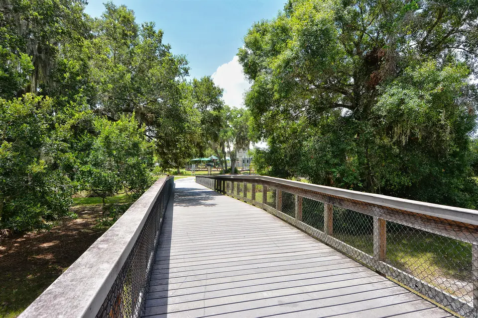 Wooden boardwalk through a shaded oak and palm park