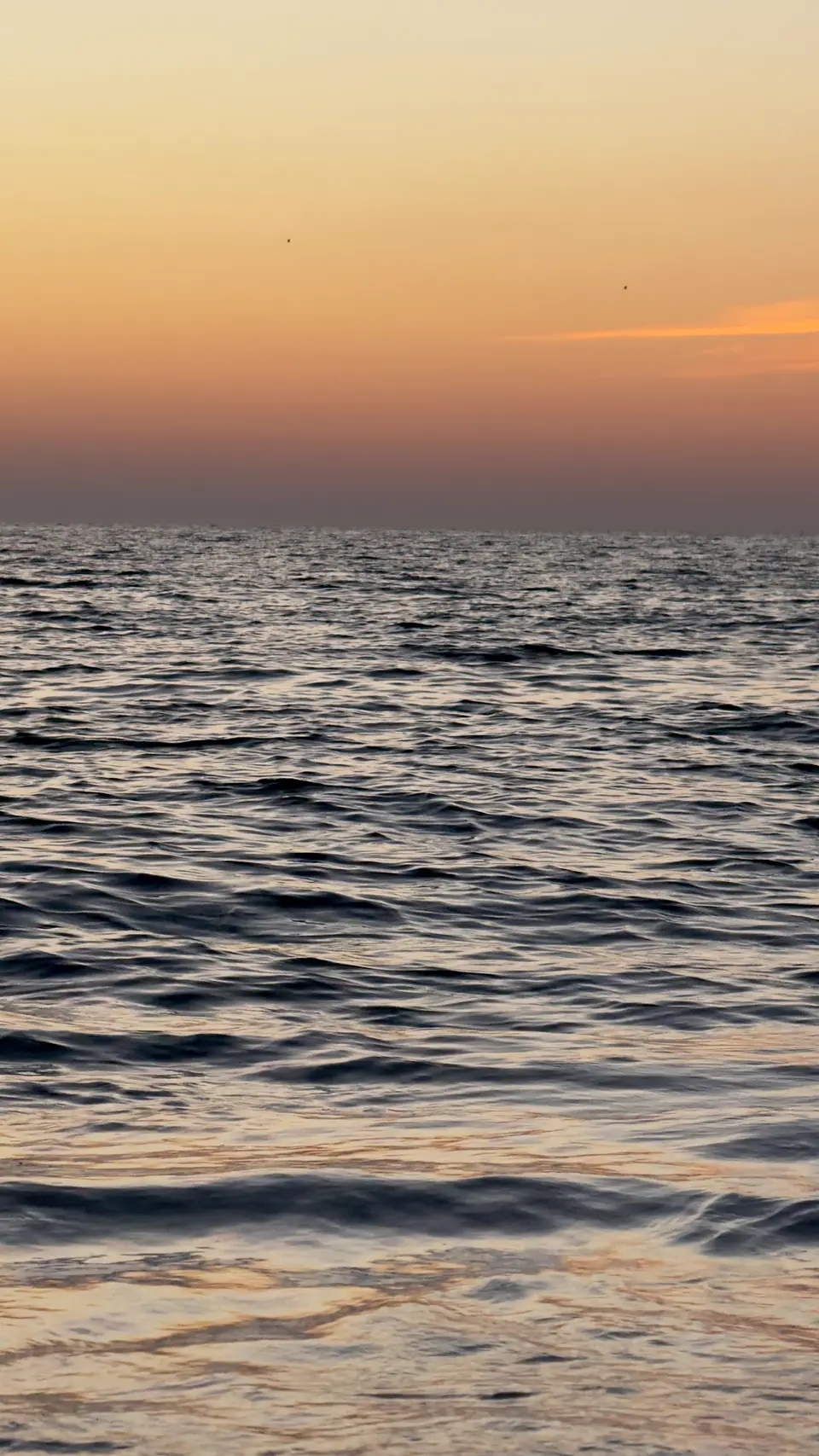 Peach sunset sky over calm rippled water
