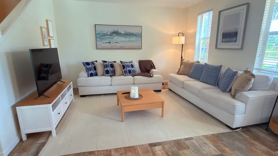 Townhome living room with neutral sectional, coffee table and wood-look floors