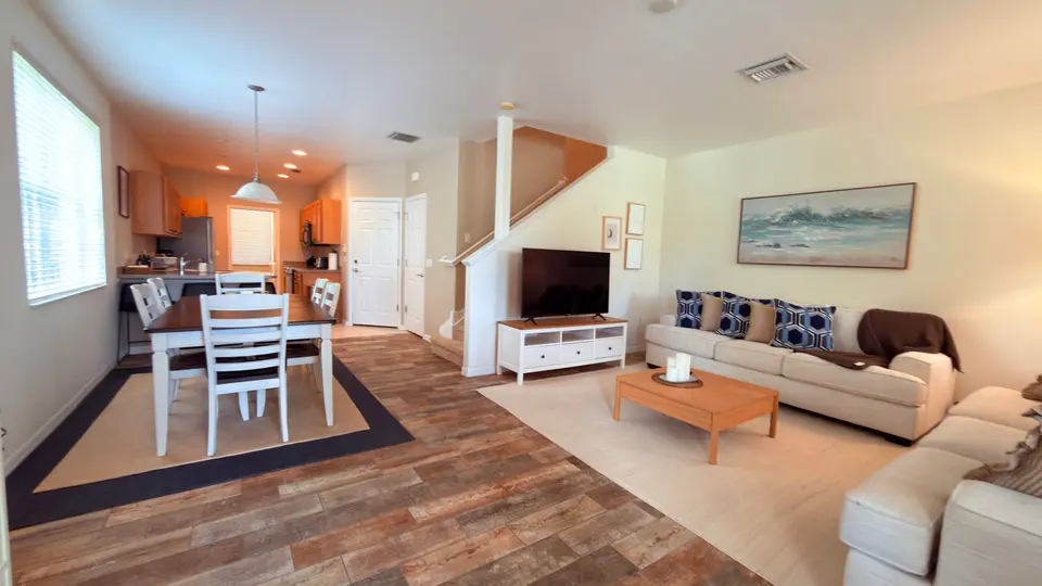 Open townhome living and dining area with stairs and kitchen beyond