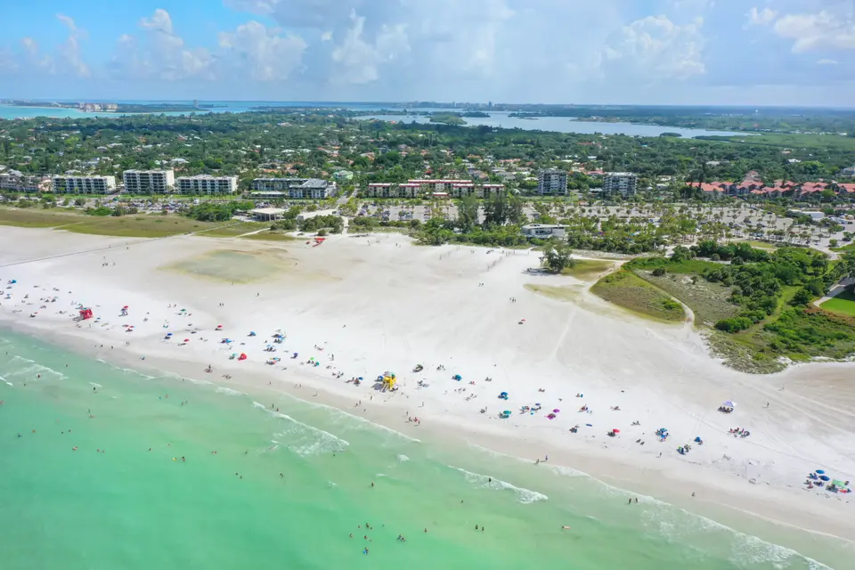 Aerial view of Siesta Beach with white sand, green Gulf water and the island behind