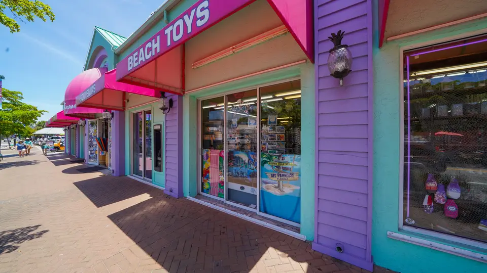 Colorful storefronts with pink awnings along a Siesta Key Village sidewalk